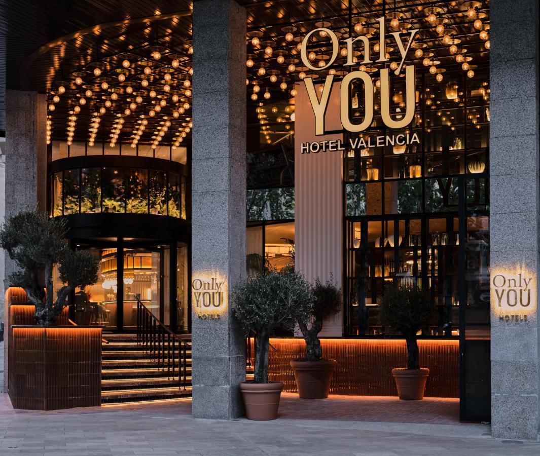 Only You Hotel Valenza Esterno foto The photo shows the entrance of a hotel named "Only YOU Hotel Valencia." The facade is modern and stylish, featuring a large, well-lit sign with the hotel name prominently displayed. The entrance is adorned with decorative lighting overhead, creating